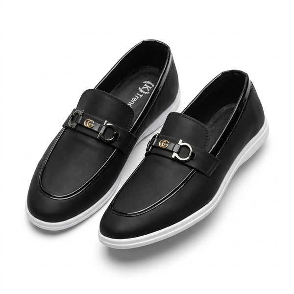 Black leather horsebit sneaker loafer pair top-down studio shot white background showing gunmetal horsebit hardware and white cupsole