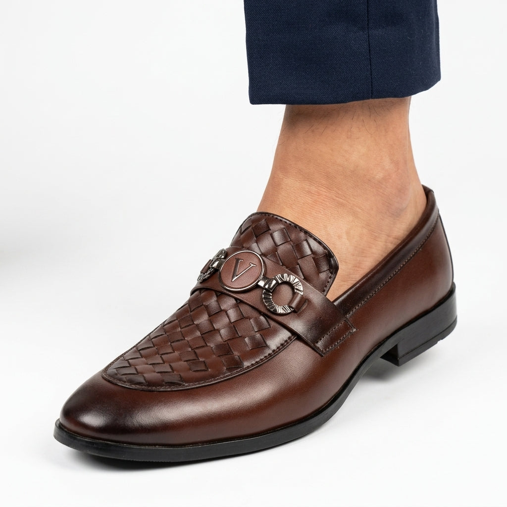 Brown woven leather logo-bit loafer with designer medallion hardware worn with navy trousers