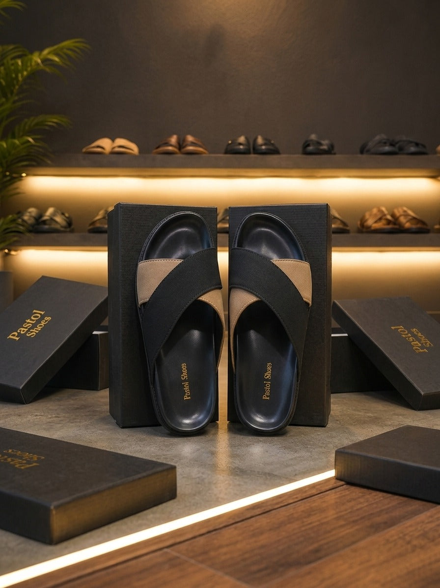 Navy and tan two-tone cross-band leather slide sandal pair held top-down showing navy moulded footbed tan suede strap and navy vamp strap in Pastol Shoes boutique