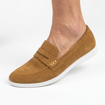 Tan suede penny loafer with white sole worn by man