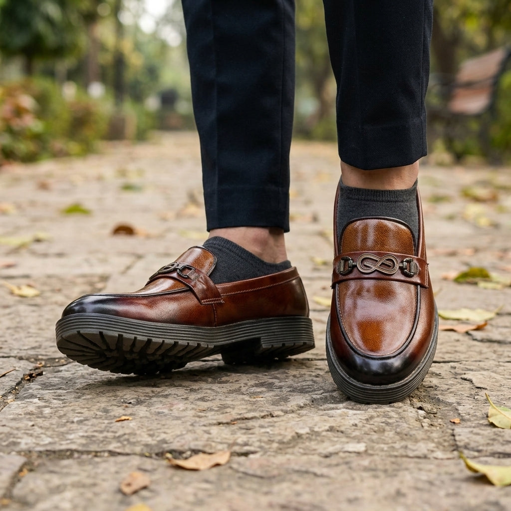 Tan burnished leather infinity-bit chunky loafer worn outdoors with navy trousers