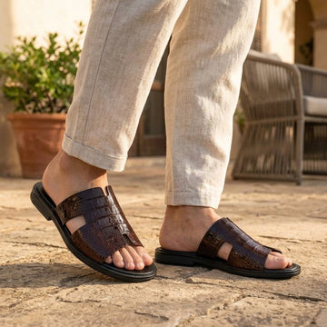Person wearing dark brown textured cross-strap sandals outdoors