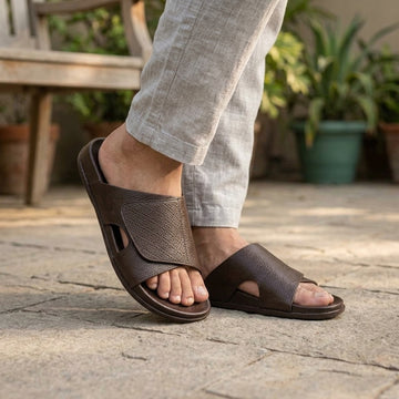 Person wearing brown cross-strap sandals outdoors