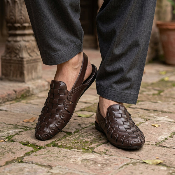 Dark brown full-woven leather slingback mule worn on ancient haveli cobblestone courtyard with charcoal shalwar kameez mid-stride