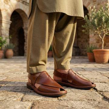 Tan cognac leather smooth-vamp Kaptaan Peshawari chappal worn on ancient stone courtyard with olive khaki shalwar kameez